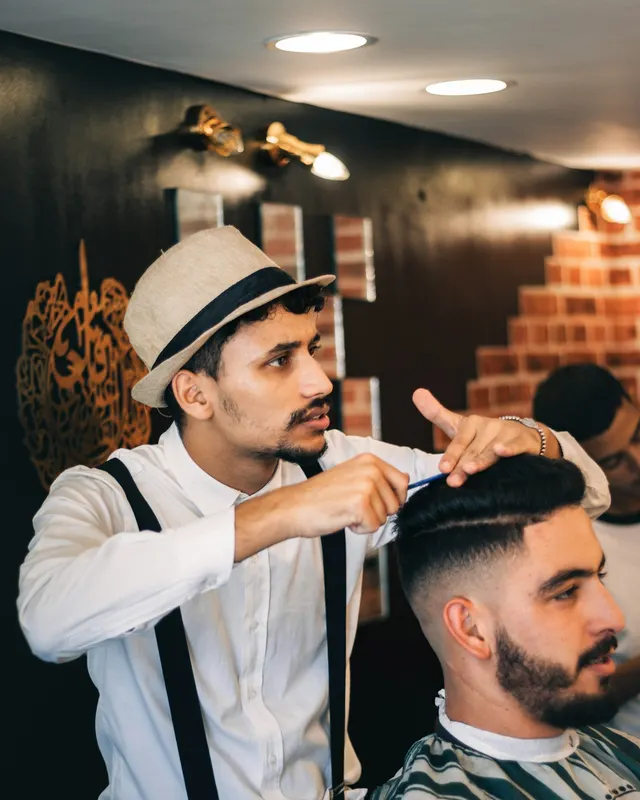 A barber finishing a customer's haircut in his shop